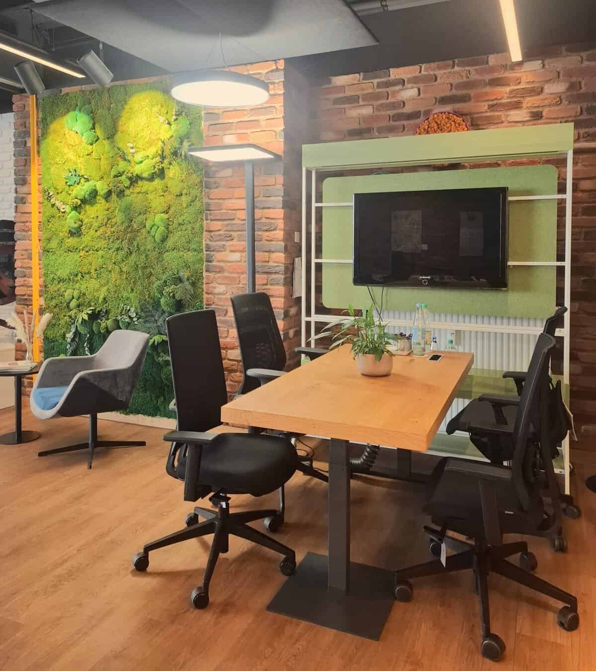 Ein Bild aus dem Showroom von Hagendorn Büroeinrichtungen. Es zeigt einen Besprechungstisch vor einer großen Mooswand.