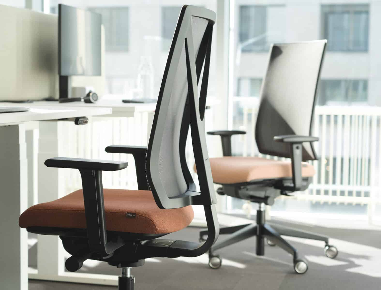 Girsberger Yanos3D Ergonomische Bürostühle vor Schreibtischen in einem hellen Büro.